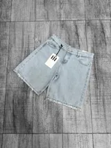Bermuda de jean de tiro medio, color celeste claro, con diseño de cinco bolsillos y terminación desmechada en las piernas.