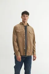 Sobrecamisa color marrón claro de pana con cuello solapa, cierre con botones a tono, dos bolsillos con tapa abotonados en el pecho y calce holgado.