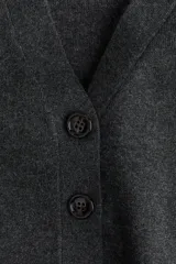 Cárdigan de punto liso color gris oscuro, con escote en V y cierre frontal de botones oscuros. Presenta un calce holgado con mangas de diseño curvo.