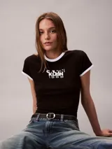 Remera Calvin Klein ajustada de manga corta, color negro con ribetes blancos en el cuello redondo y los puños. Presenta un estampado gráfico en el pecho con el texto y logo de la marca y el año 1968.
