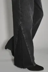Jean de corte wide leg en color negro, con diseño de paneles laterales que crean un efecto de abertura o contraste en el bajo. Posee tiro medio y cierre clásico con botón y cremallera.
