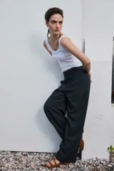 Pantalón de vestir de corte ancho y relajado, color negro con sutiles rayas diplomáticas verticales. Presenta bolsillos laterales y cierre frontal oculto.