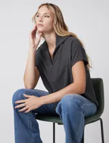 Cardigan gris jaspeado de punto de galga media, con cierre frontal metálico completo y cuello con solapa. Presenta mangas cortas de sisa caída y un corte recto y holgado que llega a la altura de la cadera.