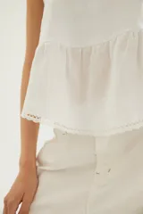 Top de lino color tostado, con breteles anchos y diseño de doble volado en el borde inferior con detalle de puntilla delicada.