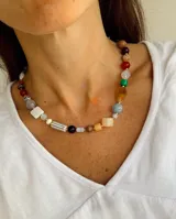 Collar de cuentas multicolor con piedras de diversas formas, tamaños y texturas, intercaladas con pequeñas esferas doradas.