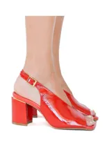 Sandalias de tacón alto en charol color rojo tomate, con punta cuadrada, taco ancho y tira ajustable en el talón con hebilla dorada.