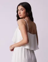 Vestido midi blanco de gasa bambula marca Lily Black, con escote redondo, breteles regulables y lazo de ajuste. Presenta una sobrecapa en el torso y un forro interno a tono. El largo de la espalda es mayor al largo delantero.