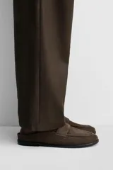 Mocasín destalonado de cuero color marrón topo con acabado serraje, antifaz en el empeine, horma redonda y suela a tono con ligero tacón.