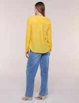 Blusa de calce relajado color salmón, confeccionada en tela liviana con textura sutil. Presenta escote en V con abotonadura frontal, bolsillo parche en el pecho, mangas largas regulables con presilla y ruedo con opción de anudar en el frente.
