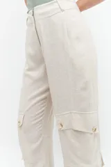 Pantalón de lino color beige melange, corte barrel, tiro alto, con bolsillos cargo laterales y cierre frontal.