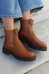 Bota tipo chelsea de cuero color chocolate, con paneles laterales elásticos y suela track de goma negra.