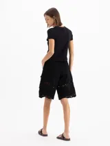 Bermuda de gabardina liviana color negro, de silueta recta y largo por arriba de la rodilla. Cuenta con bolsillos cargo laterales y detalle de encaje en el ruedo. Su acceso es mediante broches metálicos y cierre en bragueta.