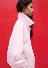 Chaqueta larga de algodón color rosado, de diseño recto con cuello solapa, manga larga, bolsillos laterales y cinturón tipo batín.