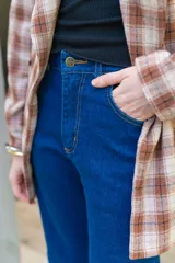Jeans de corte flare color azul oscuro, tiro alto y diseño ajustado en las piernas que se ensancha gradualmente desde las rodillas hacia el dobladillo.