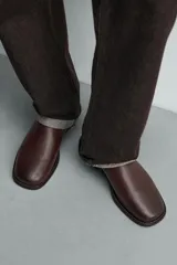 Zueco de piel color marrón oscuro, con diseño liso, horma cuadrada y suela con ligero tacón.
