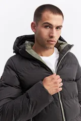 Campera puffer con capucha, diseño acolchado, cierre frontal y bolsillos laterales. Presenta un interior en contraste de color verde oliva.