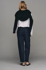 Pantalón chino de tiro bajo color marrón oscuro, con pernera recta y bajo con vuelta. Incluye un cinturón trenzado delgado de color marrón claro. Cuenta con bolsillos delanteros y cierre frontal con cremallera y botón.