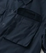 Camisa de manga corta color azul marino de corte boxy, con cuello inglés, cierre frontal de botones metálicos a presión y bolsillos cargo en el pecho.