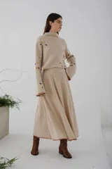 Sweater beige de tejido de punto acanalado con cuello redondo y mangas largas. Presenta apliques de manchas de colores en el frente y las mangas.