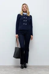 Chaqueta tejida de punto en color azul marino, con diseño de doble botonadura frontal y bolsillos aplicados. Presenta un cuello desmontable en tono claro y mangas largas.