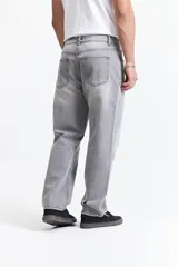 Jean de corte baggy con tiro medio, diseño amplio y holgado en piernas y cadera, con pasacintos y cierre frontal.