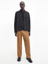 Sobrecamisa negra de sarga de algodón y nailon, corte boxy, cuello italiano, bolsillos con solapa en el pecho, billetera con botones, bajo recto, botones de gran tamaño e insignia con el logo de Calvin Klein en la manga.