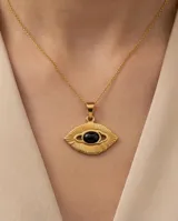 Dije de acero dorado con diseño de ojo estilizado y piedra central negra ovalada.