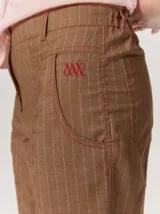 Pantalón de lino color blanco crudo, de corte barrel, con bolsillos laterales y costuras pespunteadas a contratono.