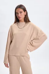 Remera de manga larga confeccionada en tejido rib, color beige, con cuello redondo y diseño de mangas anchas con corte holgado.