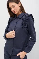 Camisa de manga larga color verde militar, con cuello clásico, cierre frontal de botones y detalle de volados en los hombros.