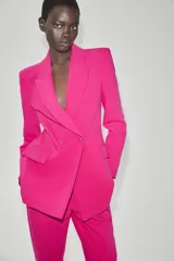 Blazer cruzado fucsia con cuello solapa, manga larga, bolsillos con solapa en el delantero y cierre frontal con botones forrados.