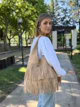 Cartera tipo hobo de cuero color beige con flecos en dos niveles.