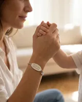 Pulsera de cadena tipo rolo en acero, con placa ovalada central grabada con la frase 'Te quiero Mamá' y dijes de corazón en los extremos.