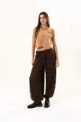 Pantalón tipo babucha de encaje color chocolate, con forro interior, cintura regulable y elásticos en los tobillos que generan una silueta abuchonada.