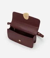 Cartera tipo shoulder bag de tamaño mediano, confeccionada en poliuretano color marrón oscuro. Presenta una solapa frontal con un detalle metálico dorado de forma orgánica y asa ajustable.