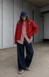 Campera oversize roja de lana, con cuello redondo, cierre frontal con botones y detalles de recortes de cuero en los hombros con bordados y tachas.