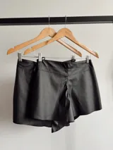 Short pollera negro de cuero sintético con detalle cruzado y lazo lateral.