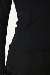 Buzo negro deportivo con capucha, cierre frontal a mitad del torso y bolsillos laterales.