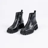 Bota corta de cuero vacuno color negro, con suela de goma tipo track y punta cuadrada. Presenta un detalle central de cuero con textura de reptil y cierre lateral interno.