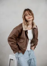 Campera de ecocuero color marrón, con forro interno de corderito sintético, cuello clásico, cierre frontal y bolsillos laterales.