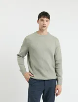 Sweater de punto en color verde claro, con cuello redondo y mangas largas. Presenta un diseño clásico de tejido liso con puños y ruedo acanalados.