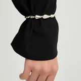 Pulsera de cuero marrón oscuro con cuentas metálicas plateadas en forma de gota y cierre de botón con grabado de la marca.