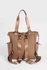 Cartera tipo shopper color marrón, con compartimento principal con cierre, bolsillos laterales, bolsillo frontal de red y cordones decorativos en color rosado. Cuenta con correas dobles de hombro y una correa extraíble de cuerda trenzada en color rosado y blanco.
