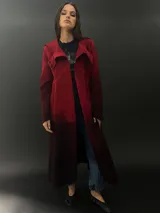 Tapado rojo con capucha, confeccionado en lana merino teñida con técnica tie-dye. Tiene corte recto, largo, bolsillos laterales y cierre cruzado con broches a presión ocultos.