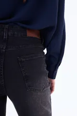 Jean de corte recto y tiro medio, confeccionado en denim negro con efecto lavado. Presenta cierre frontal con botón y bolsillos laterales.
