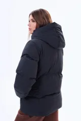 Campera puffer de corte holgado en color beige, con capucha integrada, cierre frontal completo y bolsillos laterales. Presenta un diseño acolchado con acabado mate y puños elásticos.