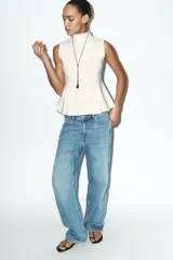 Top de punto sin mangas con cuello subido y diseño entallado con bajo en evasé tipo peplum.