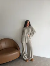 Conjunto de dos piezas color gris melange, confeccionado en tela de lanilla, compuesto por un buzo de manga larga con diseño cruzado al frente y un pantalón largo de corte holgado y tiro alto.