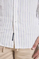 Camisa de corte regular con diseño de rayas verticales finas en tonos claros, cuello clásico y mangas largas con puños abotonados.