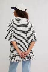 Remera oversize de punto rayada en blanco y negro, con cuello redondo, mangas cortas amplias y detalle de volado fruncido en el ruedo.